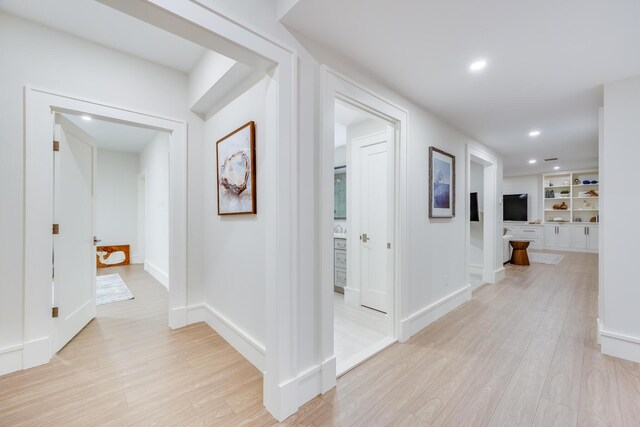 hall featuring built in shelves and light hardwood / wood-style flooring