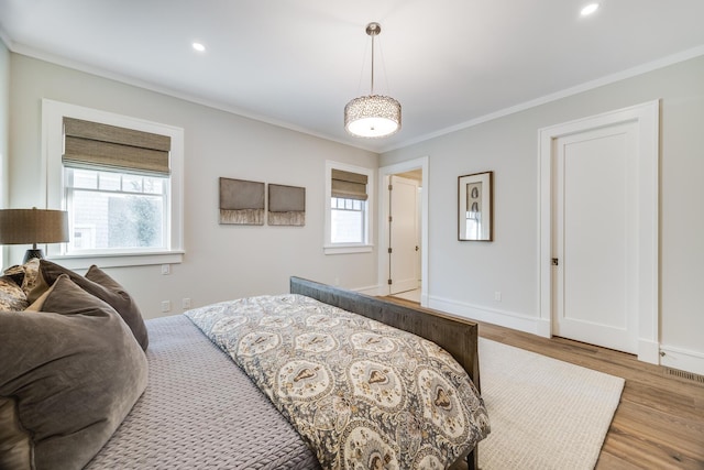 bedroom with light hardwood / wood-style flooring, multiple windows, and crown molding