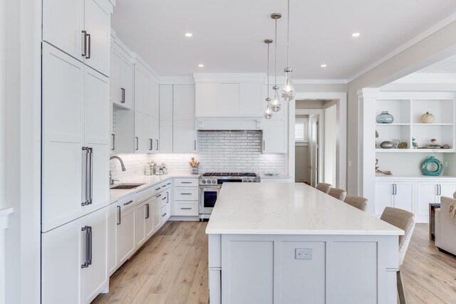 kitchen featuring light stone countertops, sink, high end stainless steel range, and a center island