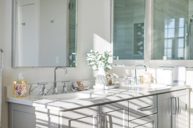 bar with sink, light stone countertops, and gray cabinets