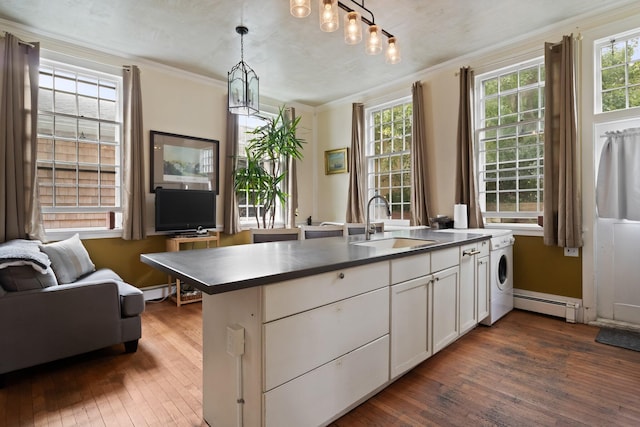 kitchen featuring white cabinets, decorative light fixtures, a baseboard heating unit, sink, and kitchen peninsula