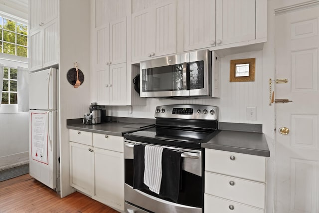 kitchen with light hardwood / wood-style floors, white cabinetry, and appliances with stainless steel finishes