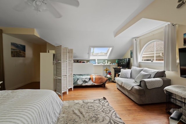 bedroom with wood-type flooring, vaulted ceiling with skylight, and ceiling fan