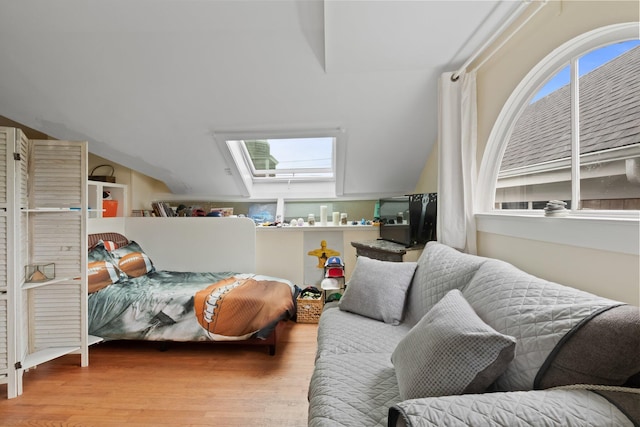 bedroom with light hardwood / wood-style floors and vaulted ceiling with skylight