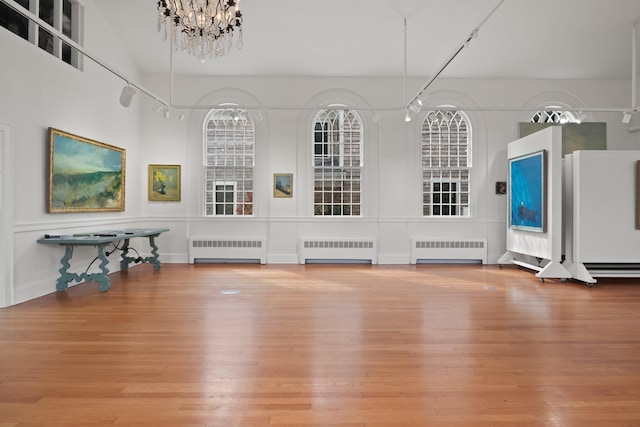 unfurnished living room featuring hardwood / wood-style flooring, radiator, and a notable chandelier