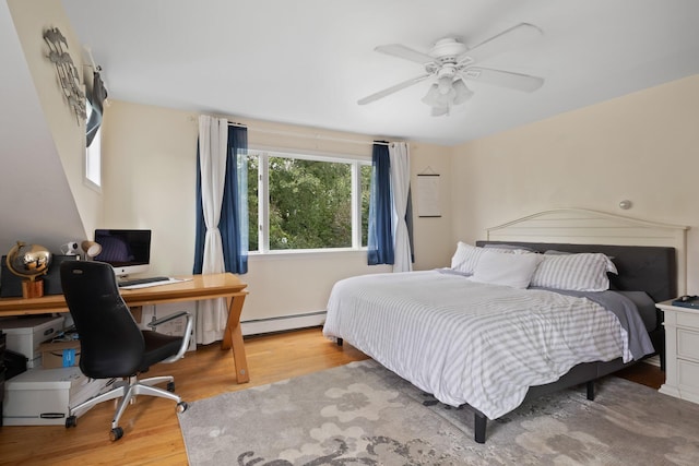 bedroom with ceiling fan, light hardwood / wood-style flooring, and a baseboard heating unit