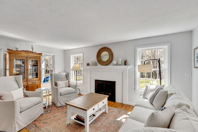 95 Red Brook Rd, Waquoit, MA 02536 - living room featuring baseboards, a textured ceiling, a fireplace, light wood finished floors, and a baseboard heating unit