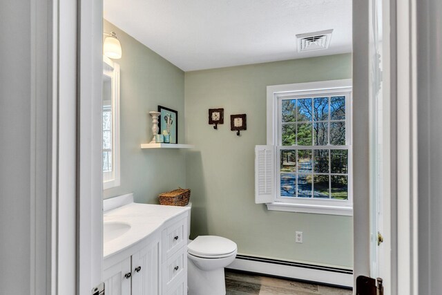 95 Red Brook Rd, Waquoit, MA 02536 - bathroom with visible vents, toilet, vanity, wood finished floors, and a baseboard heating unit