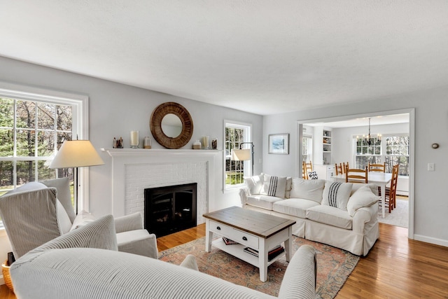 95 Red Brook Rd, Waquoit, MA 02536 - living area featuring wood finished floors, an inviting chandelier, a fireplace, and baseboards