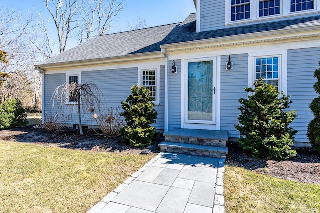 property entrance featuring a shingled roof and a yard