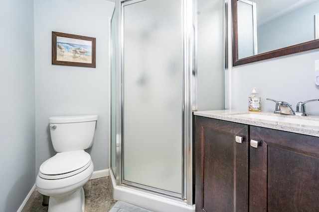 full bathroom featuring toilet, a shower stall, vanity, and baseboards