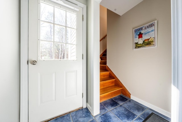 doorway featuring stone tile floors, stairway, and baseboards