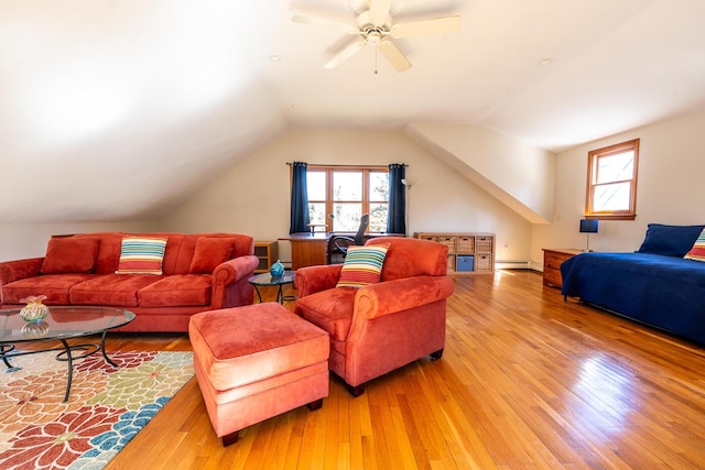 living area with lofted ceiling, a baseboard heating unit, ceiling fan, and light wood-type flooring