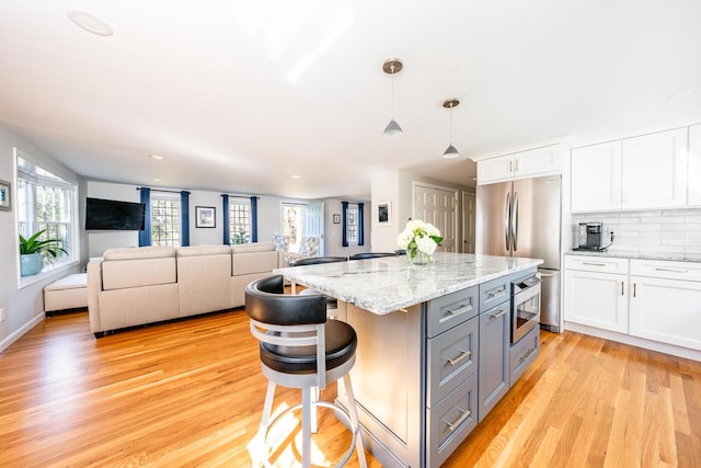 kitchen with tasteful backsplash, light wood-style flooring, gray cabinets, stainless steel appliances, and white cabinetry