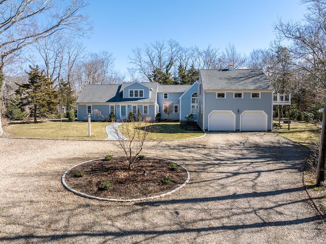 view of front of house featuring gravel driveway, a garage, and a front lawn