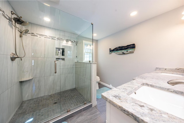 full bath with double vanity, toilet, a shower stall, a sink, and recessed lighting