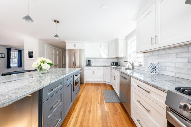 kitchen featuring plenty of natural light, white cabinets, decorative backsplash, stainless steel appliances, and a sink