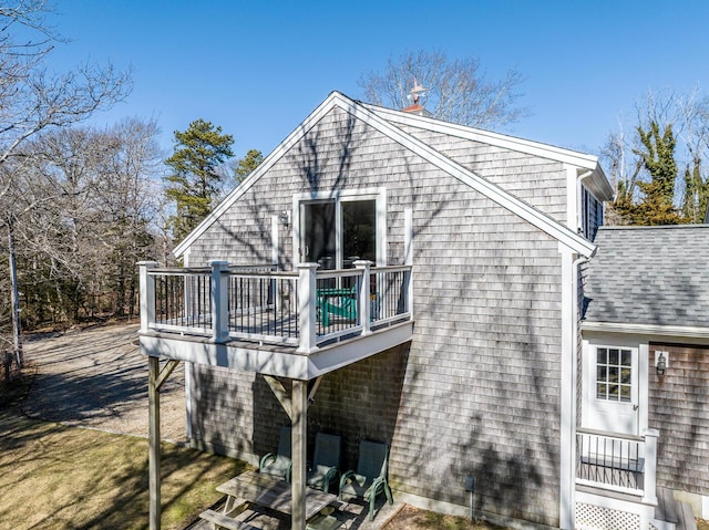 back of property featuring roof with shingles, a chimney, a wooden deck, and a lawn