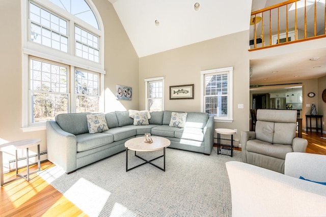 living room featuring high vaulted ceiling, a baseboard radiator, and wood finished floors