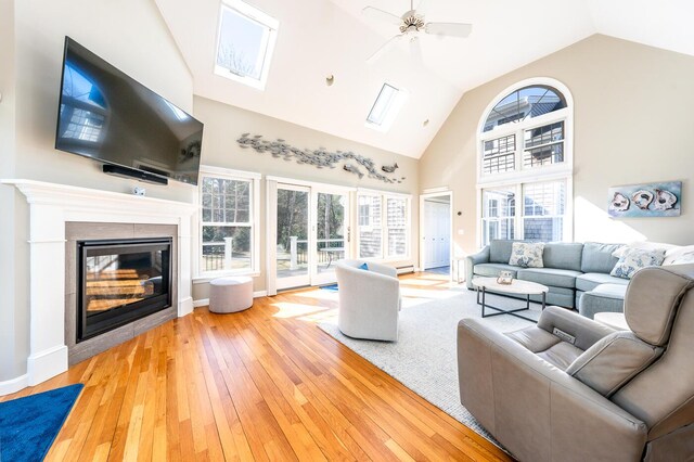 living area featuring plenty of natural light, high vaulted ceiling, wood-type flooring, and a tiled fireplace