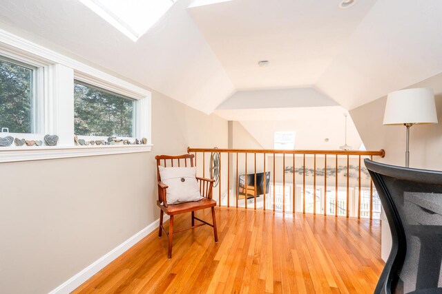 living area featuring vaulted ceiling, wood finished floors, and baseboards