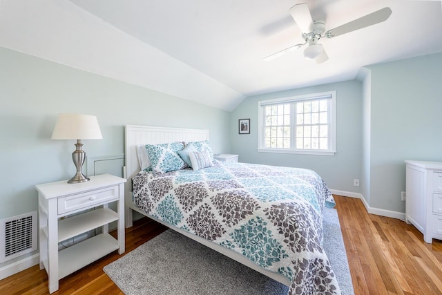 bedroom with baseboards, visible vents, lofted ceiling, ceiling fan, and wood finished floors