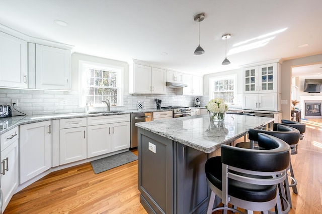 kitchen with white cabinets, appliances with stainless steel finishes, a center island, a kitchen bar, and a sink