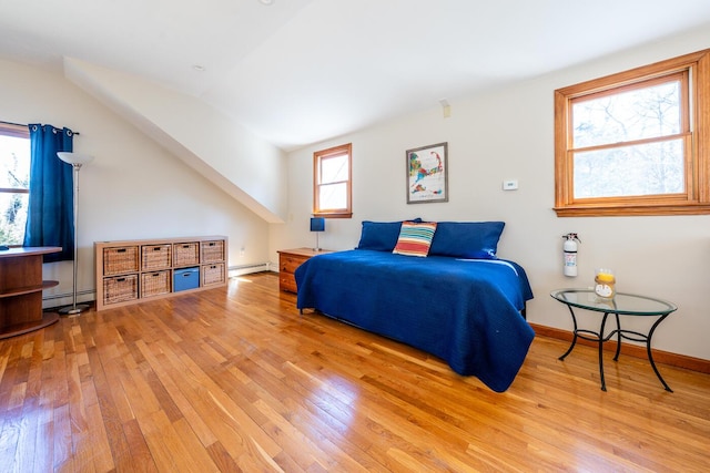 bedroom with lofted ceiling, hardwood / wood-style floors, baseboard heating, and baseboards