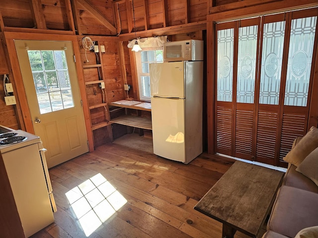 kitchen featuring hardwood / wood-style floors, wood walls, and white appliances