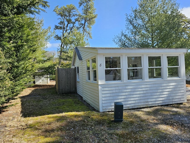 view of side of home featuring an outbuilding and fence