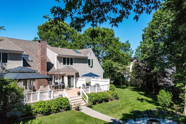 11 Polaris Dr, Mashpee, MA 02649 - view of front of house featuring a front lawn, a fire pit, a deck, and a chimney