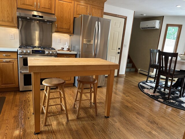 11 Polaris Dr, Mashpee, MA 02649 - kitchen with under cabinet range hood, appliances with stainless steel finishes, an AC wall unit, dark wood-style floors, and brown cabinets