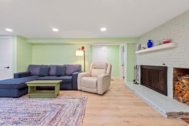 living room featuring a brick fireplace and light hardwood / wood-style flooring