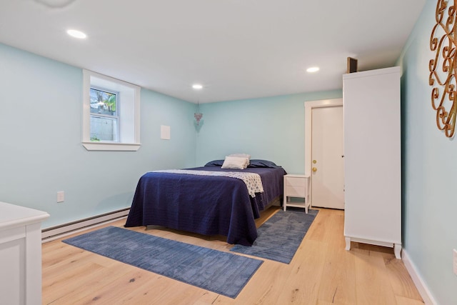 bedroom with light hardwood / wood-style floors and baseboard heating