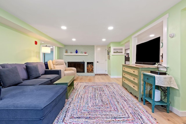 living room with a brick fireplace and light hardwood / wood-style floors