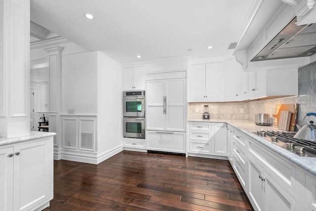 595 Main St Unit 37, Chatham, MA 02633 - kitchen featuring appliances with stainless steel finishes, ventilation hood, decorative backsplash, dark wood-type flooring, and white cabinetry