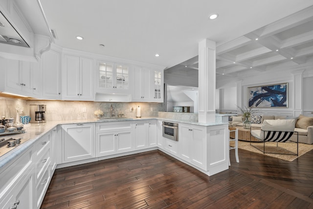 595 Main St Unit 37, Chatham, MA 02633 - kitchen featuring ornate columns, beamed ceiling, exhaust hood, backsplash, and glass insert cabinets