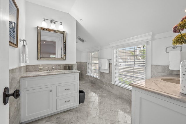 595 Main St Unit 37, Chatham, MA 02633 - bathroom featuring tile walls, two vanities, vaulted ceiling, marble finish flooring, and wainscoting