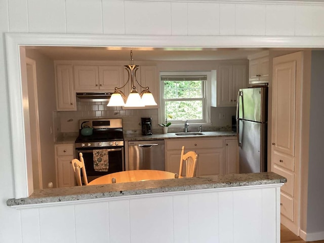 8 Saco Ave, Pocasset, MA 02559 - kitchen featuring appliances with stainless steel finishes, under cabinet range hood, light stone counters, backsplash, and pendant lighting