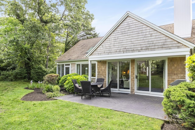 18 Juniper Cir, Brewster, MA 02631 - back of property featuring a patio area, a lawn, a shingled roof, and a chimney