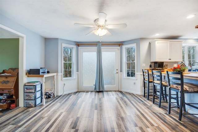 interior space with ceiling fan, sink, white cabinets, and light wood-type flooring