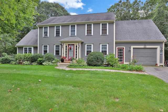 colonial home featuring a garage and a front lawn