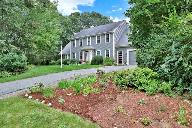 colonial inspired home with a garage and a front lawn