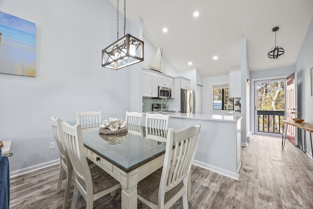 dining area featuring light wood-type flooring and vaulted ceiling