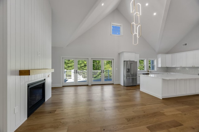 84 Hooppole Rd, Mashpee, MA 02649 - unfurnished living room with high vaulted ceiling, a large fireplace, healthy amount of natural light, french doors, and wood finished floors