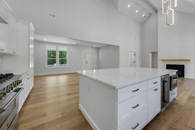 84 Hooppole Rd, Mashpee, MA 02649 - kitchen with high end stainless steel range oven, open floor plan, a center island, light wood-style flooring, and beamed ceiling