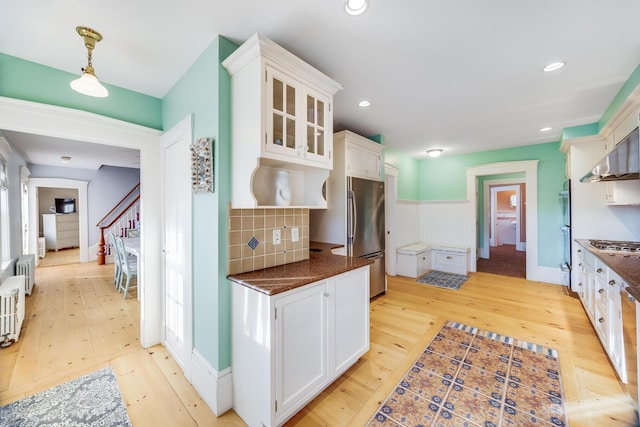 kitchen with white cabinetry, appliances with stainless steel finishes, radiator heating unit, and light hardwood / wood-style flooring