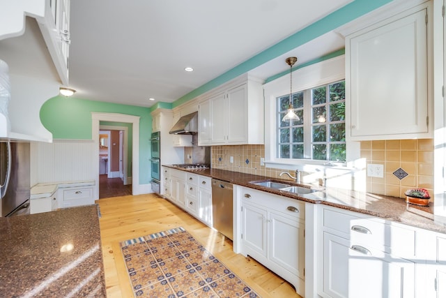 kitchen with stainless steel appliances, sink, white cabinets, and wall chimney exhaust hood