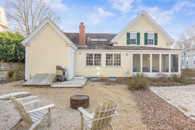 rear view of property with a sunroom and an outdoor fire pit