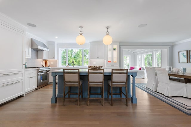 9 Joy Ln, Orleans, MA 02653 - kitchen featuring high end range, wall chimney range hood, healthy amount of natural light, white cabinets, and crown molding